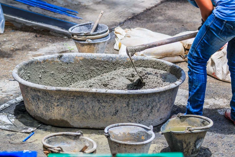 Pracovník míchá beton v velké nádrži na staveništi.