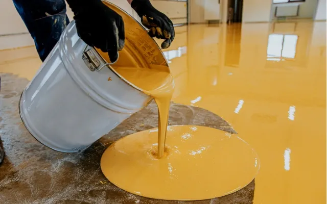 Lid nalévá žlutou epoxidovou směsí na betonovou podlahu.