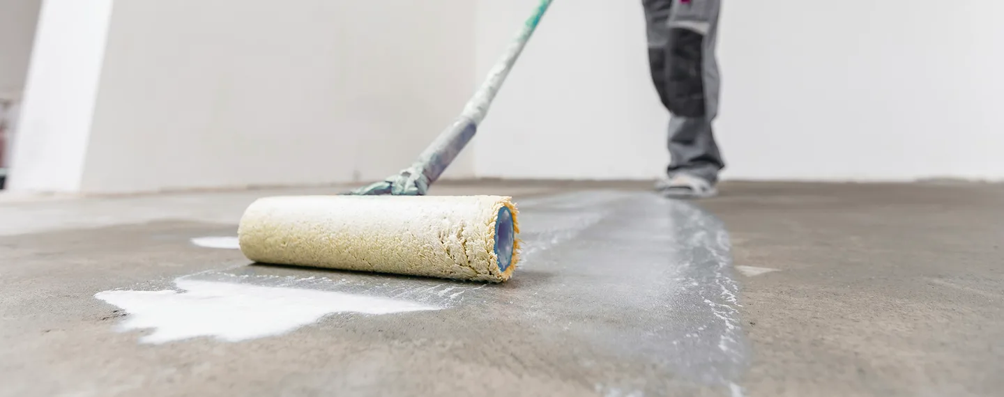 Průvodce hloubkovou penetrací: aplikátor nanáší bílou impregnaci na beton.