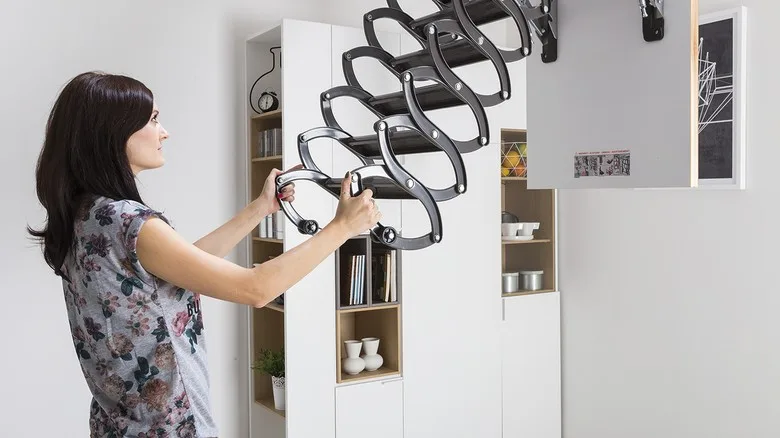 Žena instaluje skládací schodiště do podkroví.