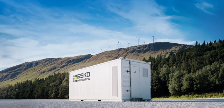 Bateriové úložiště energie s větrnými elektrárnami na pozadí.