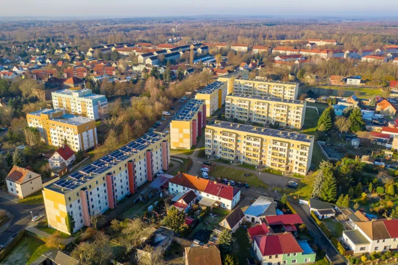 Vzdušný pohled na bytové domy s fotovoltaickými panely.