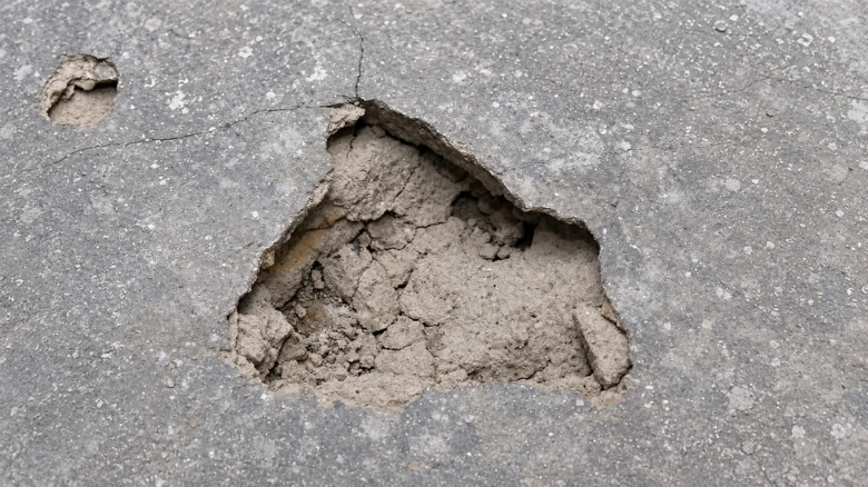 Poškozený beton s prasklinami odhalujícími podklad.