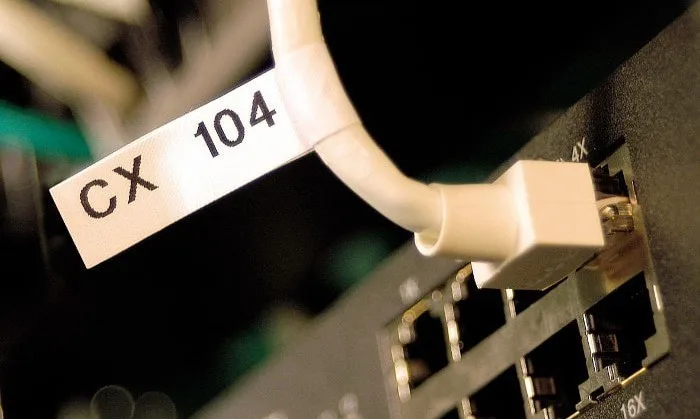 Bílá síťová kabel s popisovacím štítkem CX 104 v zásuvce.