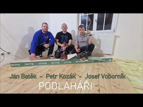 Tři pracovníci s materiálem pro vyrovnání podlahy v interiéru.