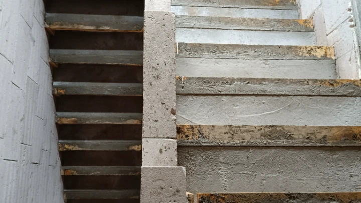 Nedokončené betonové schodiště s viditelnou konstrukcí a texturou betonu.