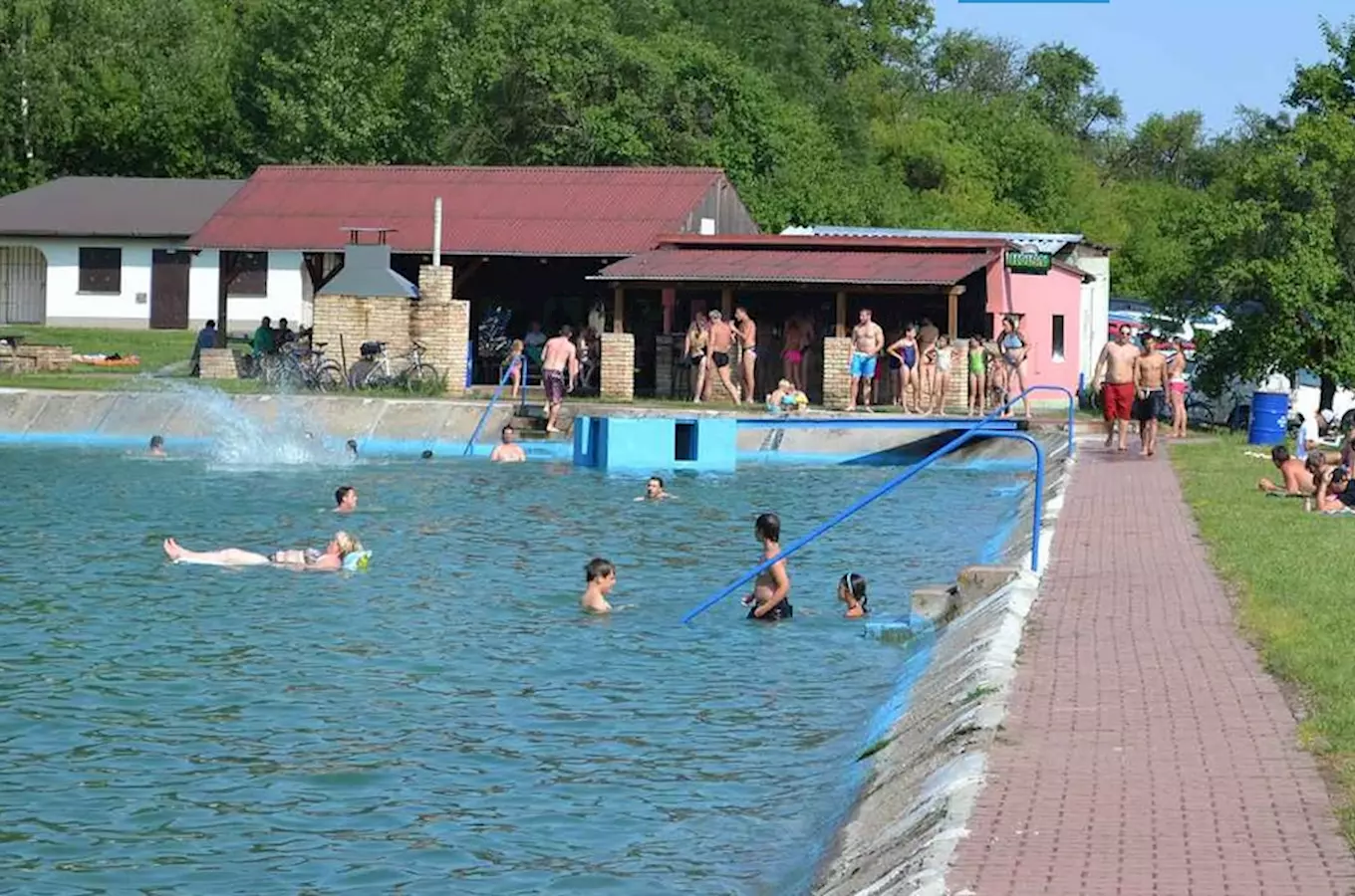 Venkovní bazén ve Všejanech s lidmi plavajícími a odpočívajícími.