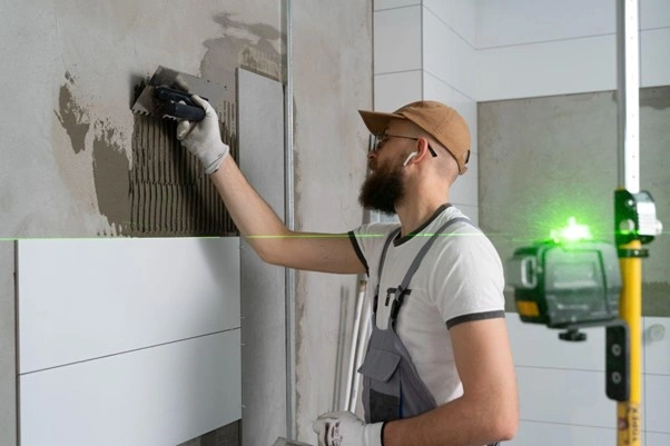 Muž leští dlaždici ve vaně pomocí laseru.