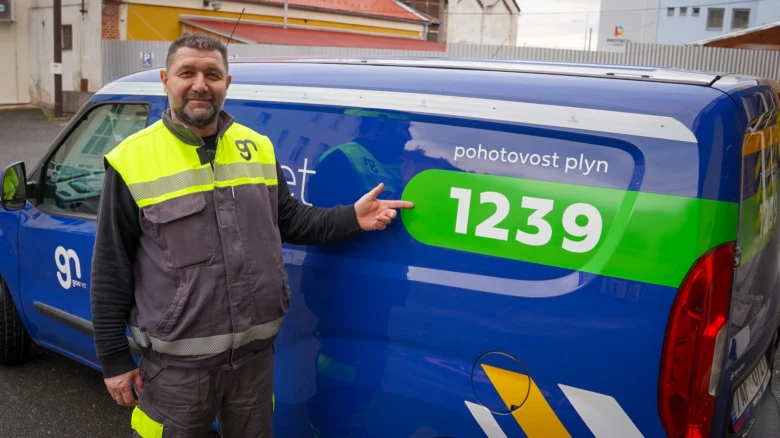 Zaměstnanec plynárenské společnosti u služebního vozu s kontaktem na pohotovost.