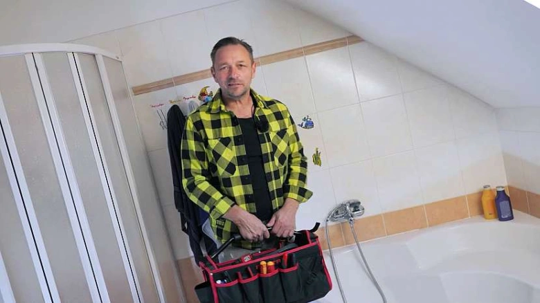 Muž s nářadím pro opravu sprchy v koupelně