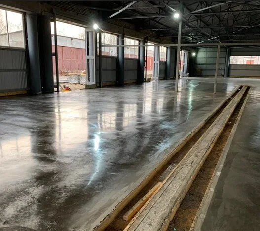 Leštěný beton v průmyslovém prostoru s odrazem světla.
