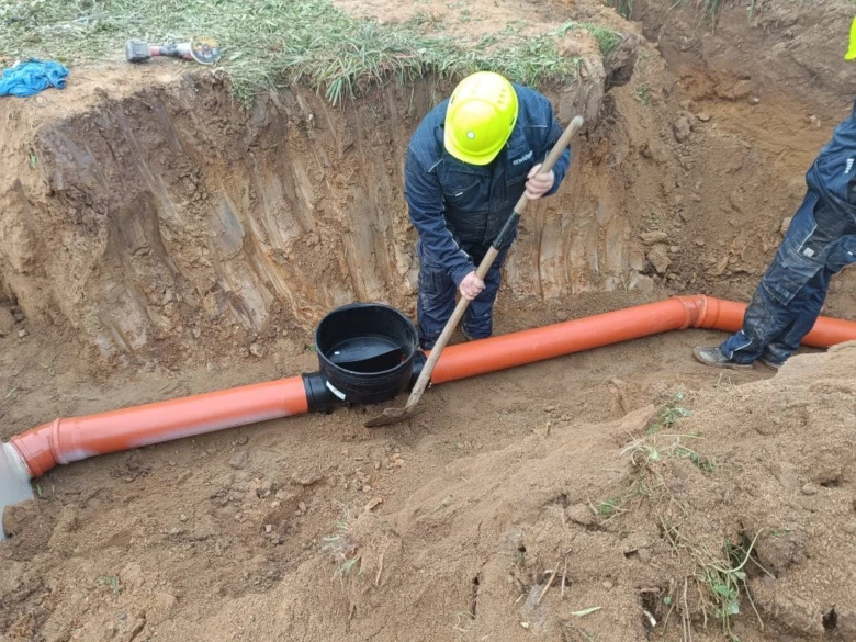 Instalace velkých oranžových odpadních trubek pro kanalizaci.