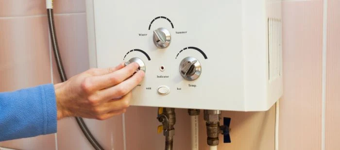 Ruka nastavuje teplotu na elektrickém bojleru v koupelně.
