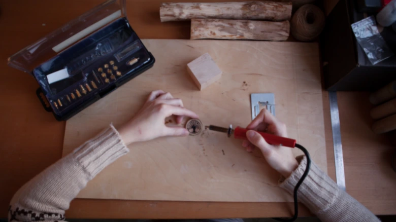 Ruční vypalování vzoru do dřeva pomocí elektrického nástroje.