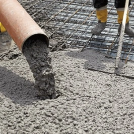 Svěží beton se nalévá na ocelovou výztuž pro stavbu.
