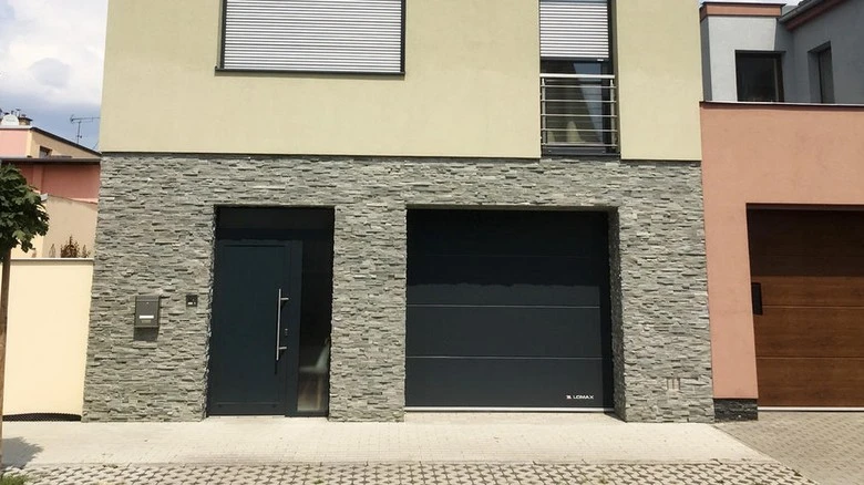 Moderná garážová brána vedle vchodu na fasádě domu.