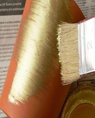 Křemenná barva se nanáší štětcem na oranžový povrch.
