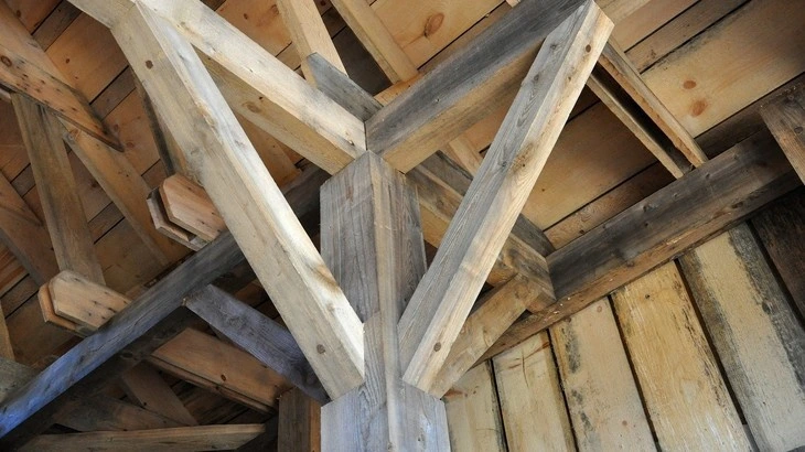 Detail dřevěných trámů tvořících střechu tradičního stavení.