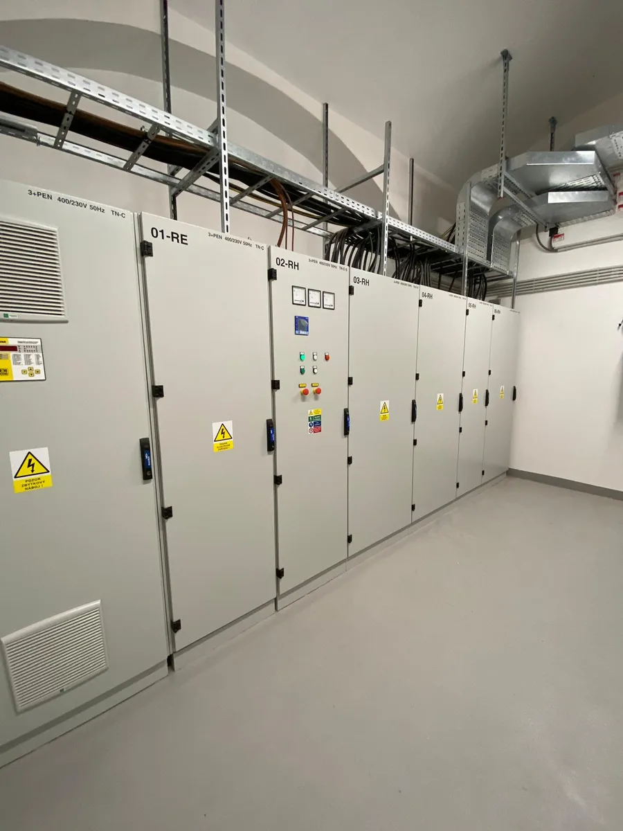 Řada průmyslových elektrických rozváděčů v čistém technickém prostoru.