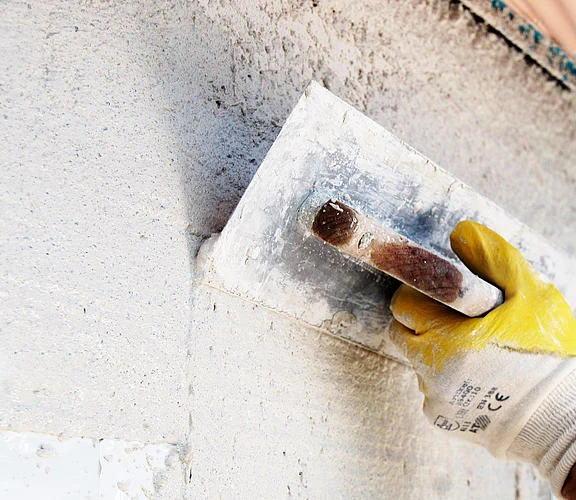 Hand applying plaster with trowel