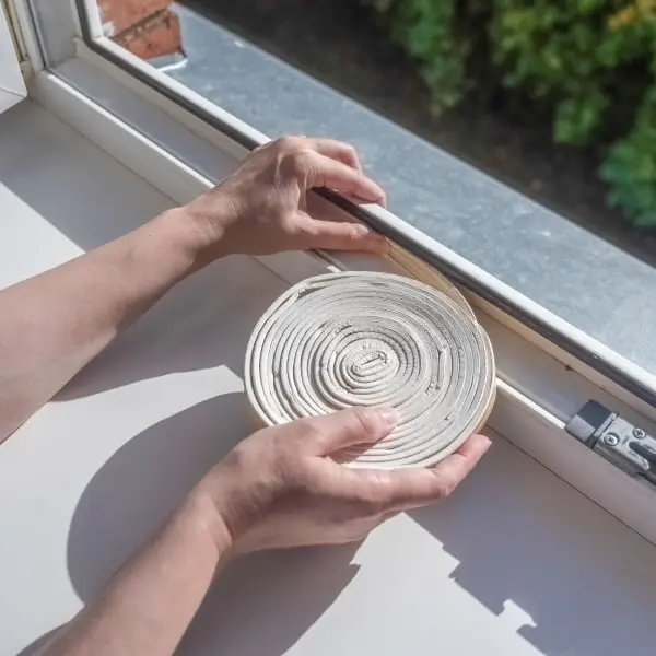 Ruční instalace těsnicí pásky do oken na okenním rámu.