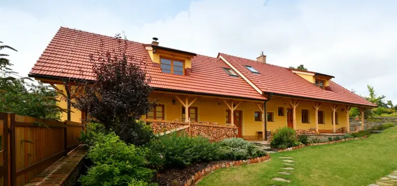 Žlutý dům s červenohnědou keramickou střešní krytinou.