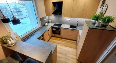 Moderní kuchyně s integrovaným barem pro stolování u okna.