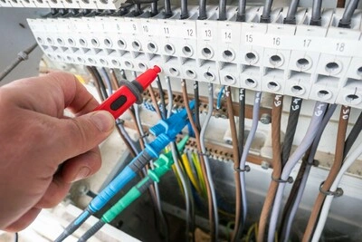 Ruční měření napětí v rozvaděči při revizi elektroinstalace.