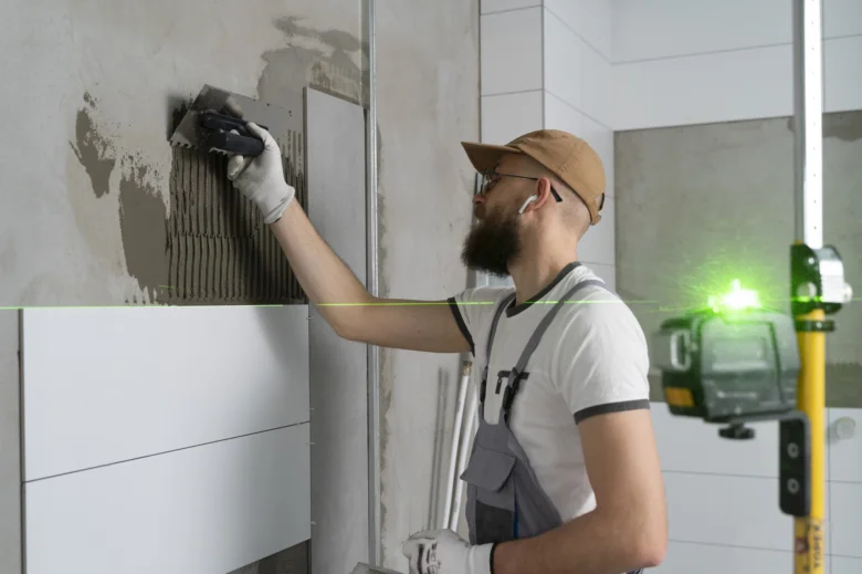 Stavebník lemuje dlažbu ve vanové místnosti s použitím laseru.