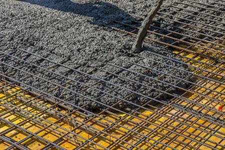 Čerstvý beton se nalévá na ocelovou výztuž v žluté podkladové desce.