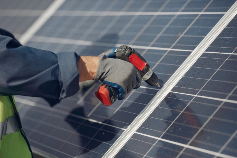 Montáž fotovoltaického panelu pomocí vrtáku při instalaci.