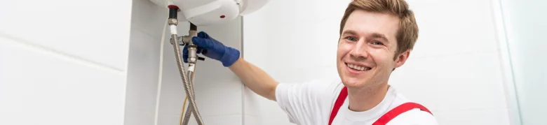 Montér připojuje bojler na vodovodní potrubí v koupelně.