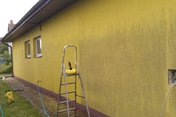 Čištění žluté fasády s použitím schodiště a čističe tlakovou vodou.