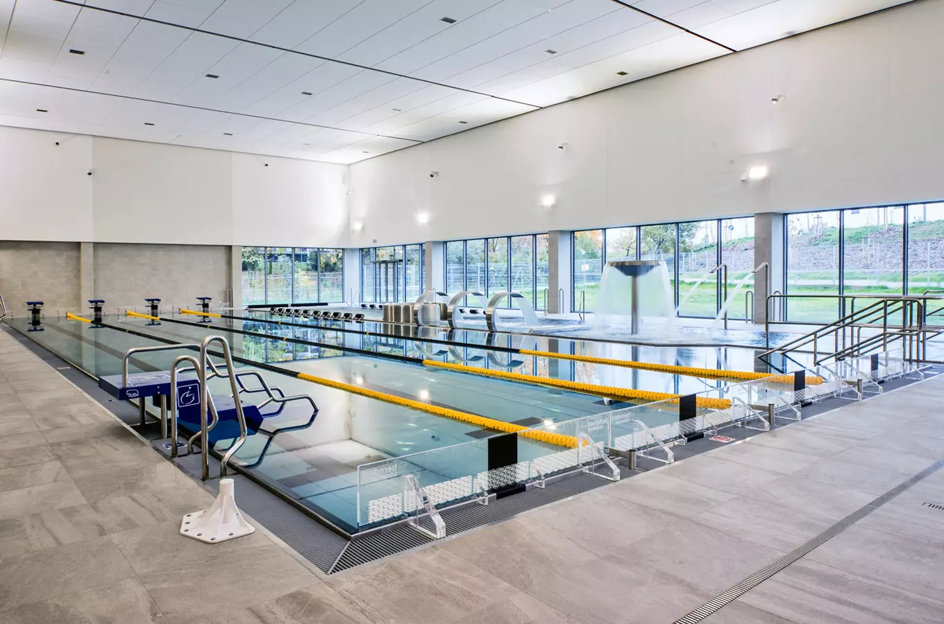 Moderní plavecký bazén s více dráhami uvnitř sportovního centra.