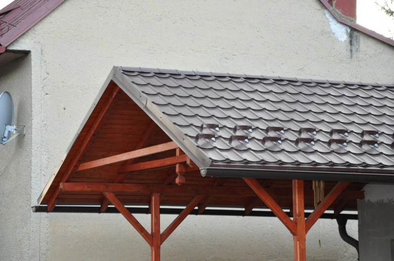 Montáž oplechování střechy s dřevěným rámem na fasádě domu.
