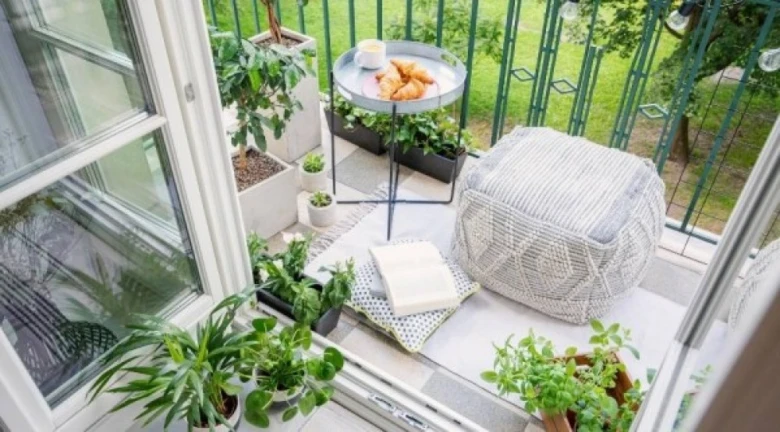 Zelený balkon s rostlinami, polštářem a dekorací pro inspiraci.