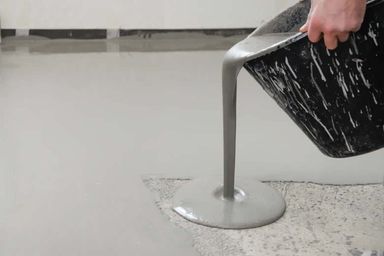 Nalévání samonivelační směsi na podlahu pro vyrovnání povrchu.