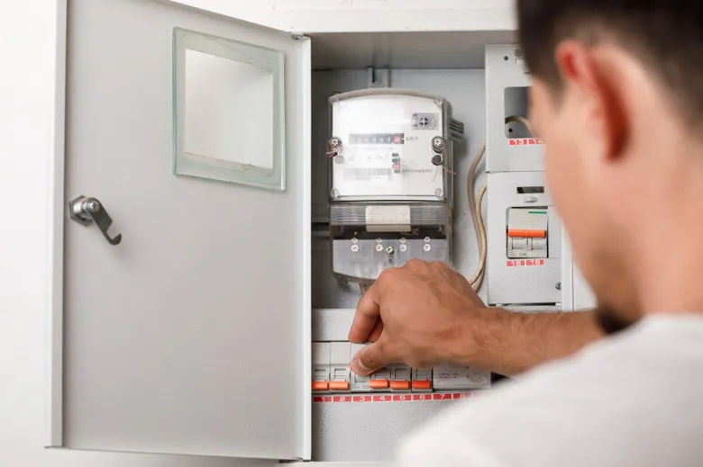 Elektrikář upravuje jistič v rozvaděči s měřidlem.