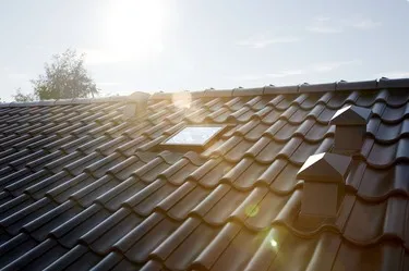 Střecha s oknem světlovodu a větracími prvky na slunci.