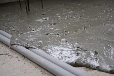 Mokrý bílý cement se rozlévá na podlahu během aplikace.