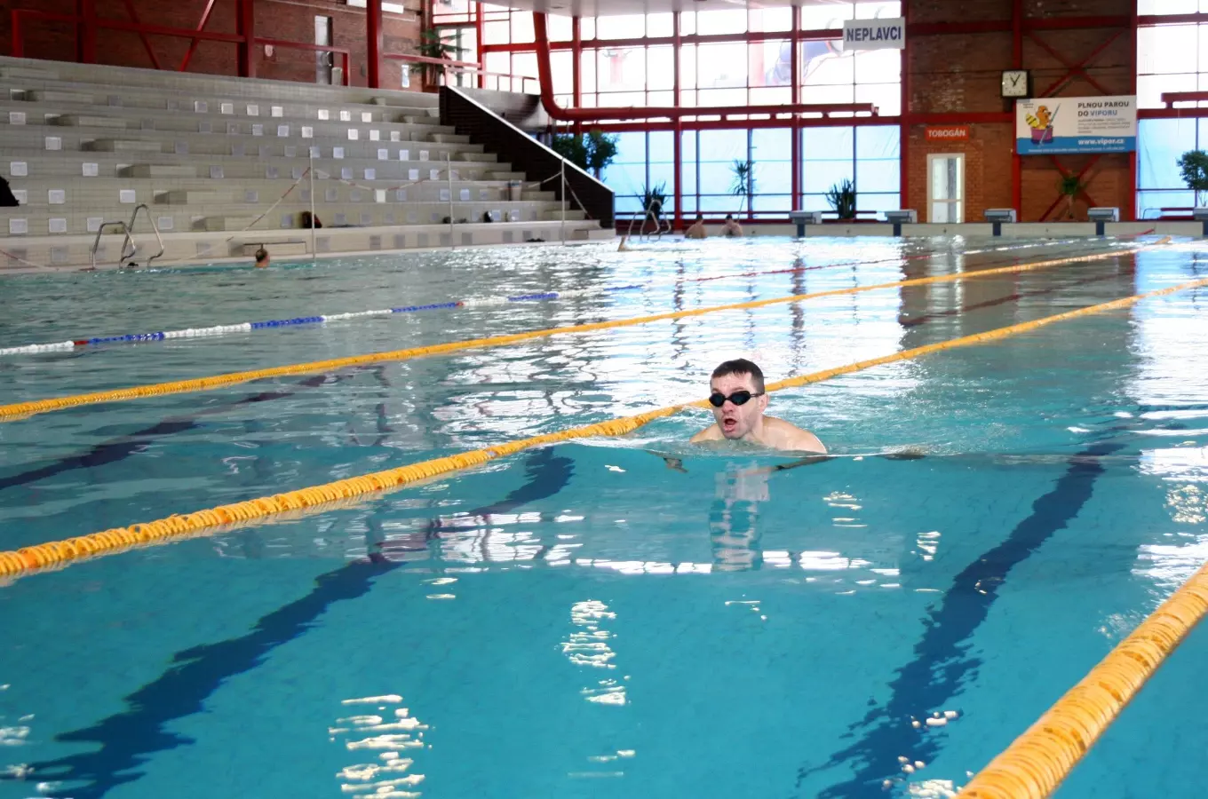 Muž plave na zádech v krytém bazénu v Ostravě-Porubě.