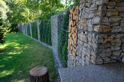 Kámen v drátěných košících tvoří zdi s dřevem vedle.