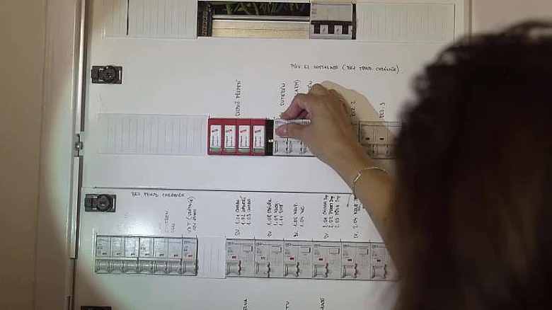 Osoba přepíná pojistku v rozvaděči pro zapojení elektrického obvodu.