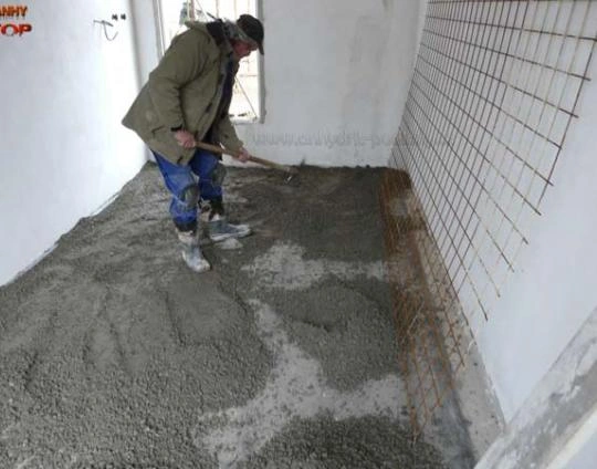Muž nalévá betonovou podlahu s výztuhou na stěně