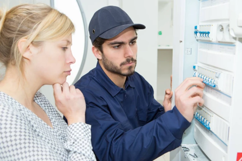 Elektrikář kontrolová jističe v rozvaděči pro elektroinstalaci.