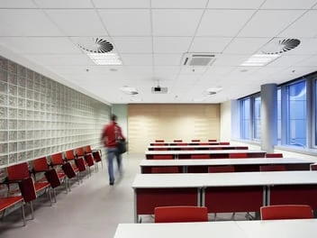 Moderní interiér s kazetovým stropem v učebně nebo konferenčním místnosti.