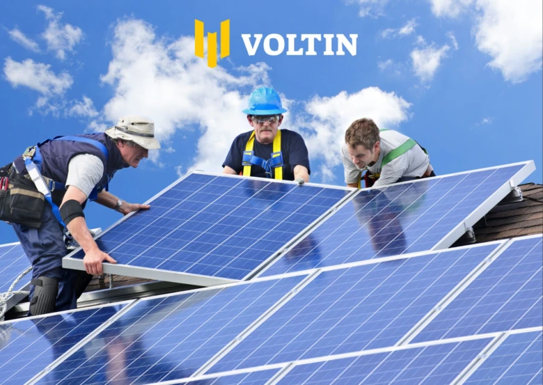 Montáž fotovoltaických panelů na střechu pracovníky v ochranném obleku.
