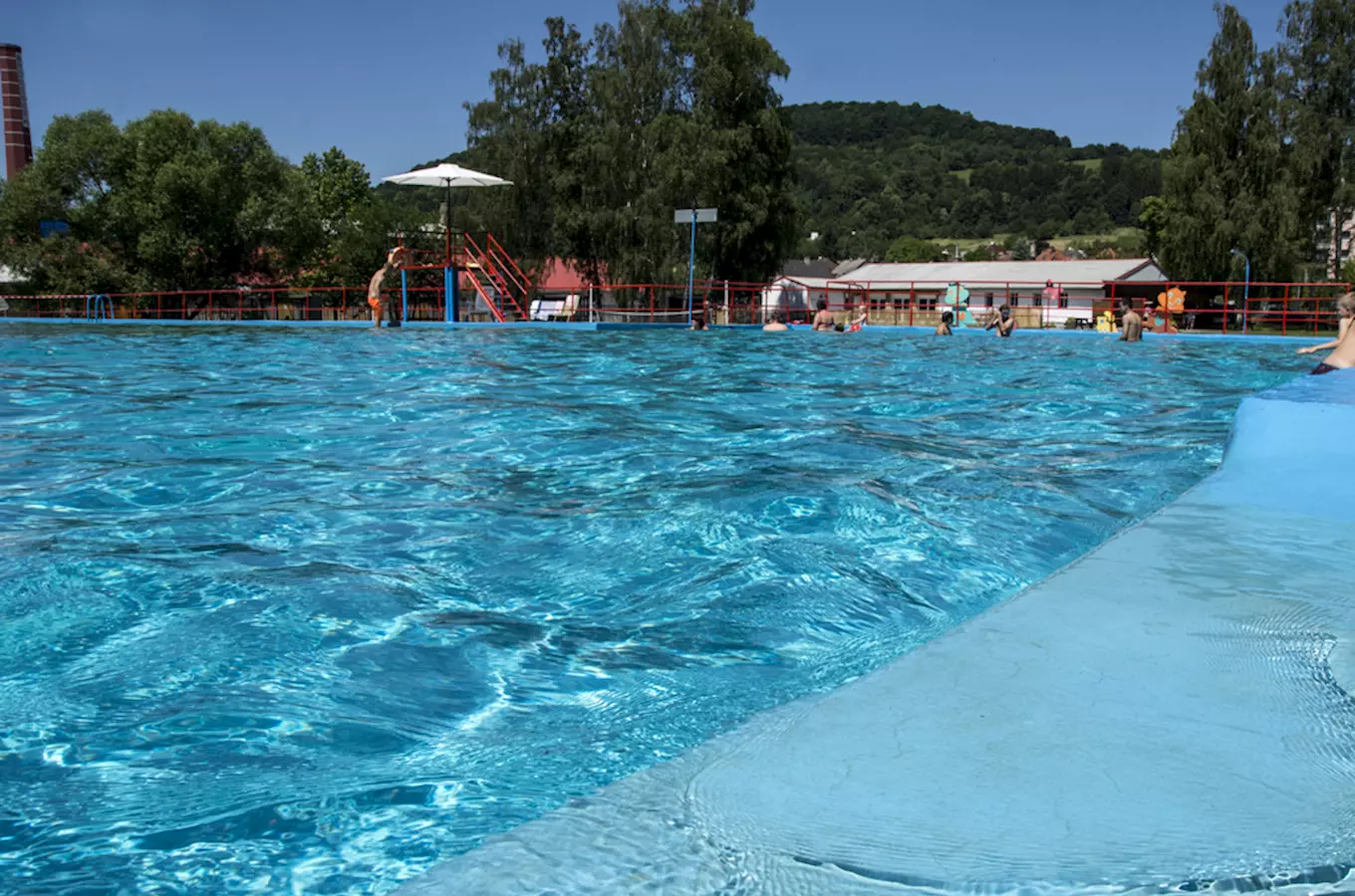 Venkovní bazén v Benešově nad Ploučnicí s lidmi ve vodě.