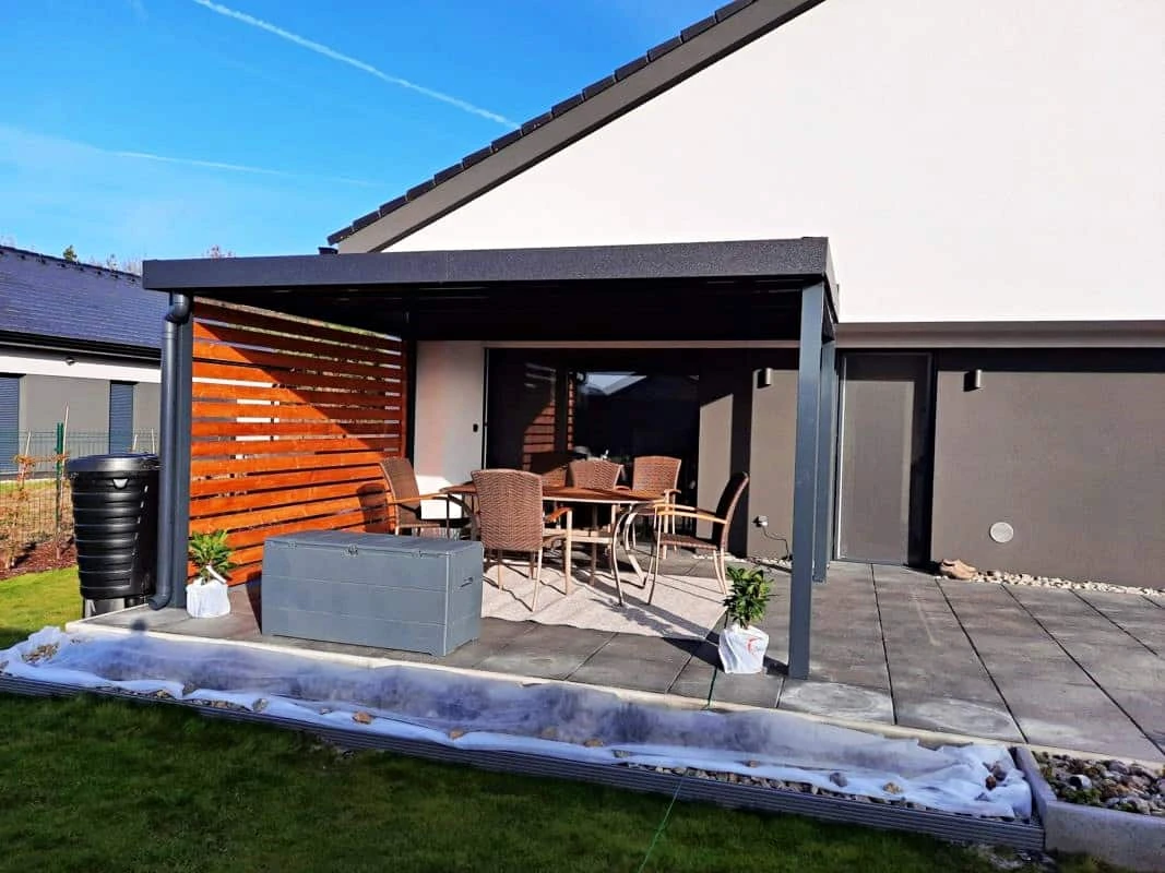 Dřevěná pergola s venkovním jídelním stolem na zahradě.