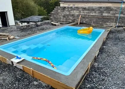 Nově nainstalovaný nadzemní bazén s dřevěným rámem na štěrku.